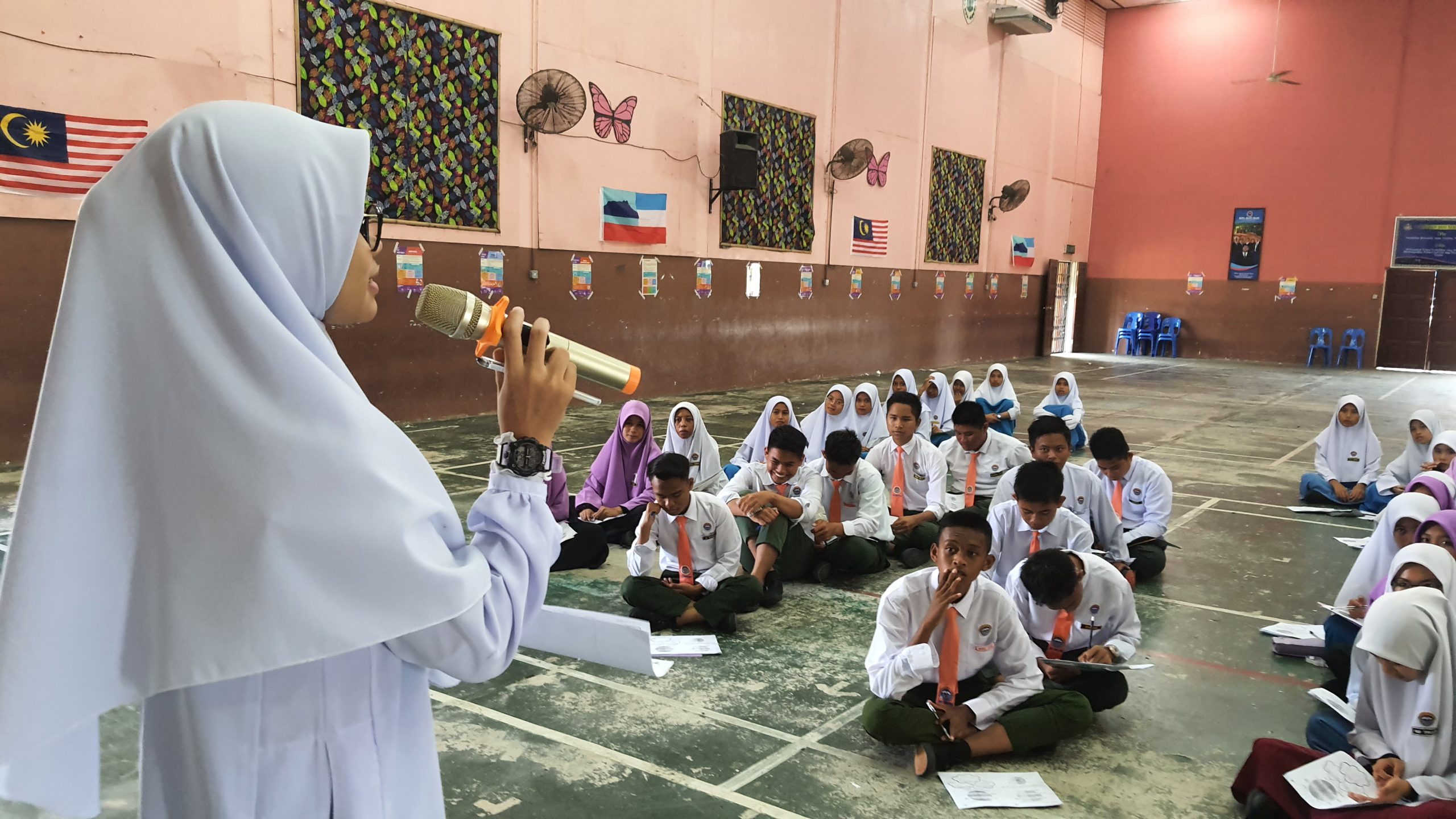 A student speaking into a microphone in front of a group of students