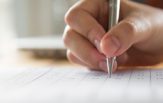 A hand writing on paper with a pen